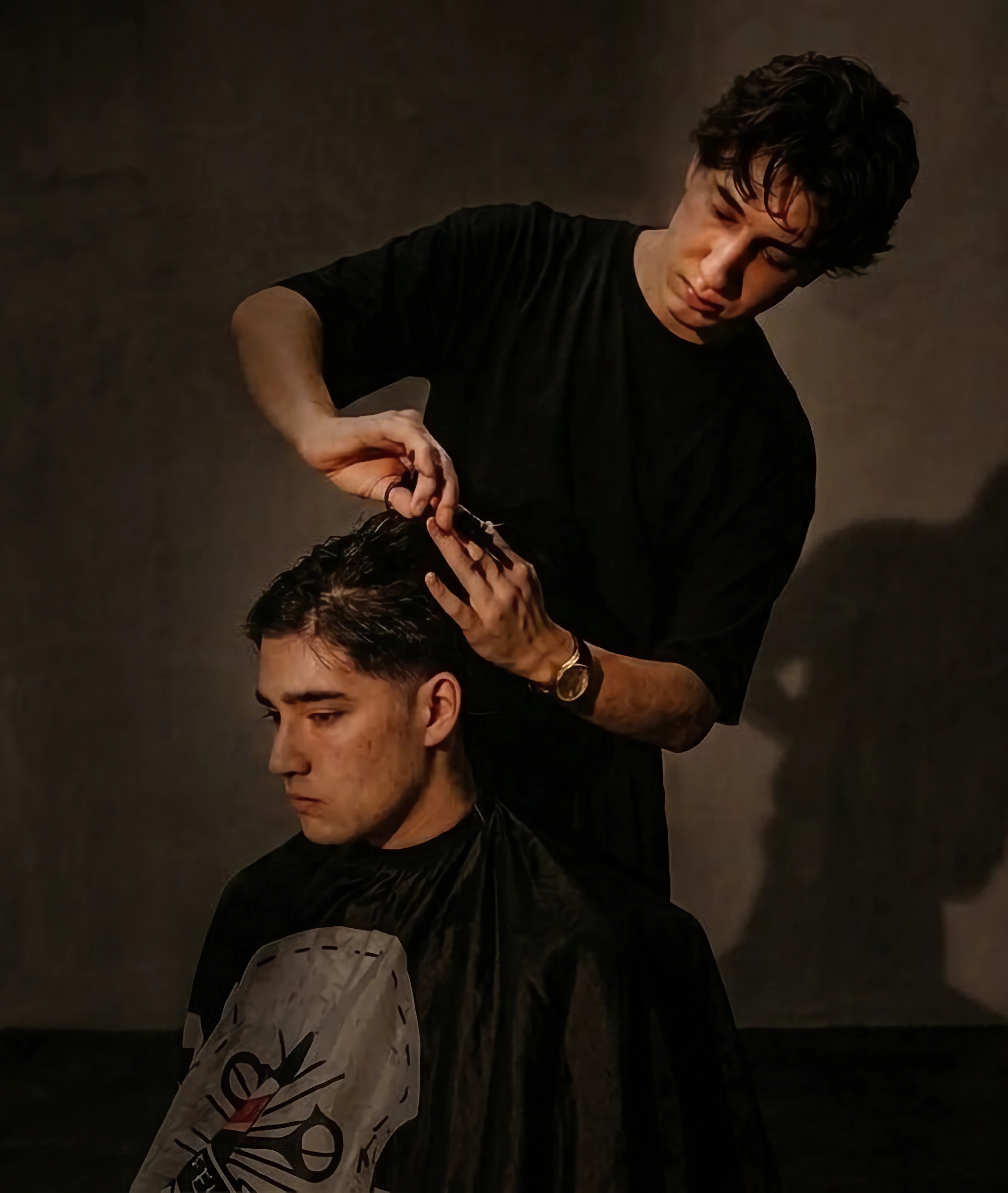 Barber carefully cutting a client's hair in a dark, upscale barbershop